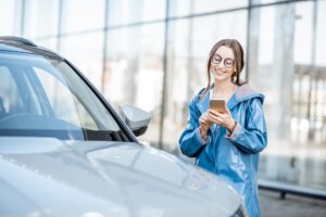 Woman with phone near the car outdoors